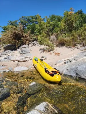 a yellow kayak sitting on the rocks in the water at Casa del lago los molinos in La Estancia