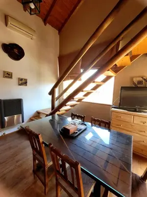 a dining room with a wooden table and a kitchen at Posada Vientos de Belgrano in Villa General Belgrano