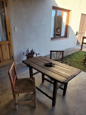 a wooden table and a chair and a wooden table and a bench at Posada Vientos de Belgrano in Villa General Belgrano
