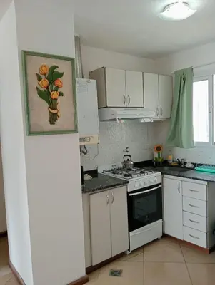 a kitchen with white cabinets and a stove top oven at Nenu Villa Carlos Paz Departamento Céntrico piscina in Villa Carlos Paz