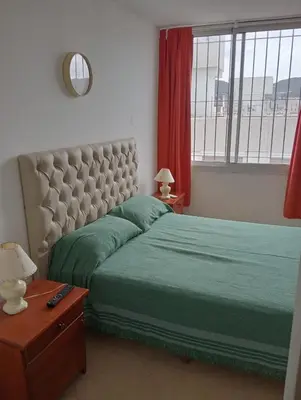 a bedroom with a bed with green sheets and a window at Nenu Villa Carlos Paz Departamento Céntrico piscina in Villa Carlos Paz