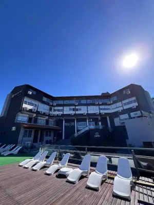 a row of white chairs on a deck with a building at Hotel y Cabañas Capri in Villa Carlos Paz