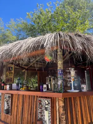 a bar with a straw umbrella on top of it at Hotel y Cabañas Capri in Villa Carlos Paz