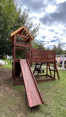 a wooden bench and a play structure in a park at Hotel y Cabañas Capri in Villa Carlos Paz