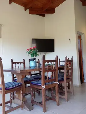 a wooden dining room table with chairs and a tv at Wualküre, acogedora cabaña en Villa General Belgrano in Villa General Belgrano