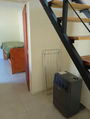 a room with a staircase with a computer and a heater at Wualküre, acogedora cabaña en Villa General Belgrano in Villa General Belgrano