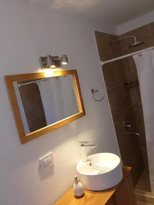 a bathroom with a sink and a mirror and a shower at Wualküre, acogedora cabaña en Villa General Belgrano in Villa General Belgrano