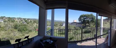 a room with a balcony with a view of a house at Wualküre, acogedora cabaña en Villa General Belgrano in Villa General Belgrano