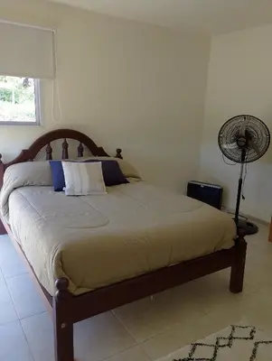 a bedroom with a bed with a fan and a lamp at Wualküre, acogedora cabaña en Villa General Belgrano in Villa General Belgrano