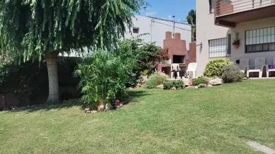 a yard with a tree and chairs and a house at Samay in Villa Carlos Paz
