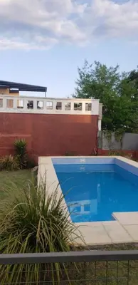 a large blue swimming pool in front of a building at Samay in Villa Carlos Paz