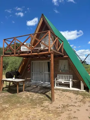 a large green roofed house with a bench and a table at Complejo Ayün in Travesía