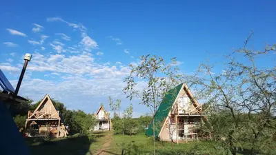 a group of huts in a field under a blue sky at Complejo Ayün in Travesía
