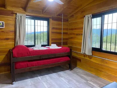 a bedroom with a red bed in a room with windows at Terrazas del Algarrobo in Santa Rosa de Calamuchita