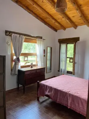 a bedroom with a bed and a dresser and a window at Casa de campo La Chunia in Villa Cura Brochero