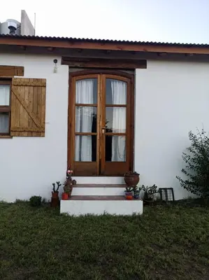 a white house with a wooden door and stairs at Casa de campo La Chunia in Villa Cura Brochero