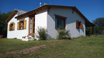 a small white house with a cross on the roof at Casa de campo La Chunia in Villa Cura Brochero