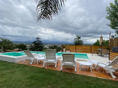 a deck with chairs and a swimming pool at Residencia Premium con Vista Panorámica y Pileta Climatizada in Villa Carlos Paz