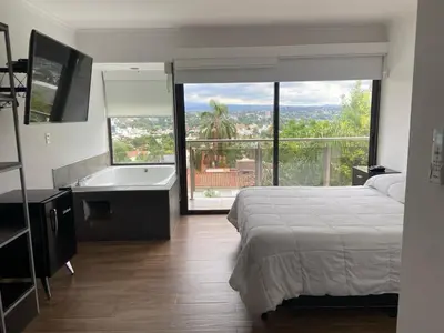 a bedroom with a bed and a bath tub and a television at Residencia Premium con Vista Panorámica y Pileta Climatizada in Villa Carlos Paz