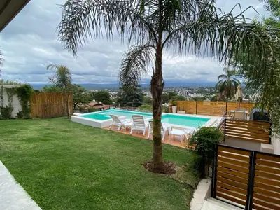 a pool with chairs and a palm tree in a yard at Residencia Premium con Vista Panorámica y Pileta Climatizada in Villa Carlos Paz