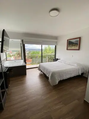 a bedroom with a bed and a desk and a window at Residencia Premium con Vista Panorámica y Pileta Climatizada in Villa Carlos Paz