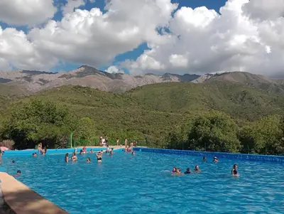 people in a swimming pool with mountains in the background at Tacuarita in Los Hornillos