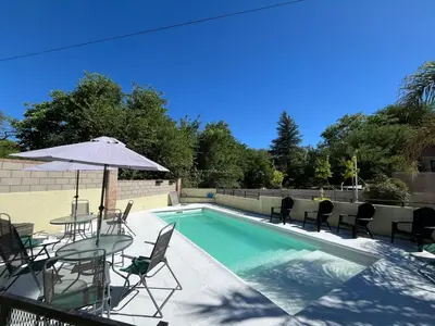 a pool with chairs and a table and an umbrella at Sol y Río in Villa Carlos Paz