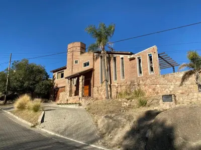 an old brick house with palm trees on a street at Casa de Categoria, Villa Del Lago, Cap 8 pers in Villa Carlos Paz