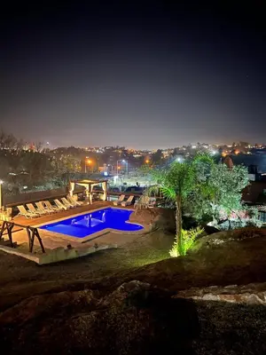 a swimming pool with chairs around it at night at Casa de Categoria, Villa Del Lago, Cap 8 pers in Villa Carlos Paz