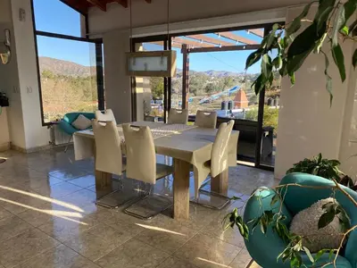 a dining table and chairs in a room with a view at Casa de Categoria, Villa Del Lago, Cap 8 pers in Villa Carlos Paz