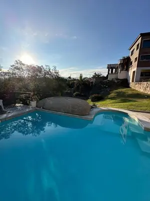 a large blue swimming pool in front of a house at Casa de Categoria, Villa Del Lago, Cap 8 pers in Villa Carlos Paz