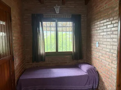 a bed in a brick room with a window at Cabaña Los Nogales- Naturaleza y relax en Altas Cumbres in Arroyo de Los Patos