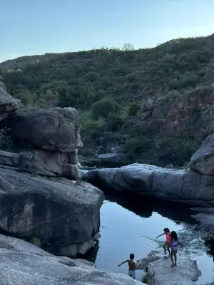 three people playing in the water on the rocks at Cabaña Los Nogales- Naturaleza y relax en Altas Cumbres in Arroyo de Los Patos