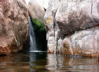 a waterfall on the side of some rocks in the water at Cabaña Los Nogales- Naturaleza y relax en Altas Cumbres in Arroyo de Los Patos