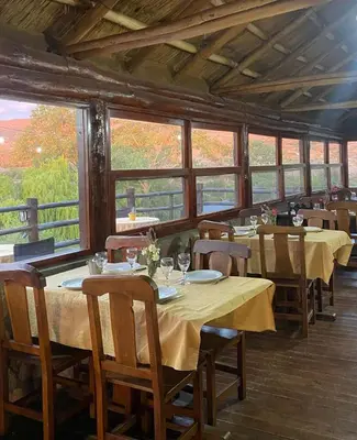 a dining room with tables and chairs and windows at Cabaña Los Nogales- Naturaleza y relax en Altas Cumbres in Arroyo de Los Patos