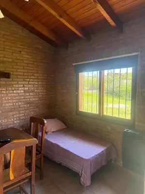 a small bedroom with a bed and a window at Cabaña Los Nogales- Naturaleza y relax en Altas Cumbres in Arroyo de Los Patos
