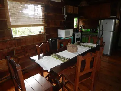 a kitchen with a table with chairs and a refrigerator at Cabañas El Atalaya in Villa Rumipal
