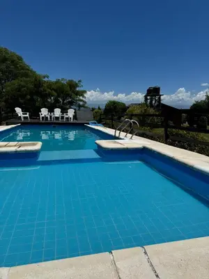 a large swimming pool with blue tiles on it at Cabañas El Atalaya in Villa Rumipal