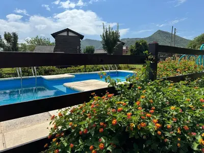 a garden with a swimming pool and some flowers at Cabañas El Atalaya in Villa Rumipal