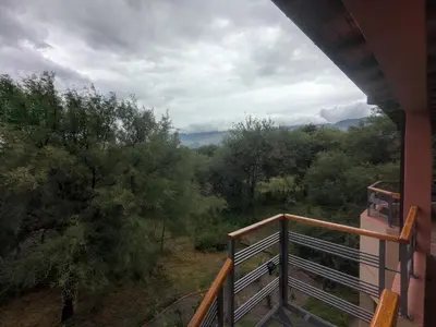a balcony of a house with a view of a forest at Posada Abrazo Serrano en Carpintería in Carpintería