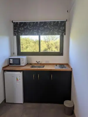 a kitchen with a sink and a window with a microwave at Posada Abrazo Serrano en Carpintería in Carpintería