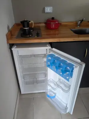 a small refrigerator with its door open in a kitchen at Posada Abrazo Serrano en Carpintería in Carpintería