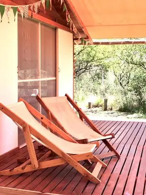 a wooden chair sitting on a deck on a porch at Glamping Traslasierra Carpa Sur in San Javier