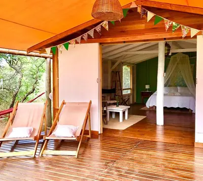 a room with a bed and chairs on a wooden floor at Glamping Traslasierra Carpa Sur in San Javier