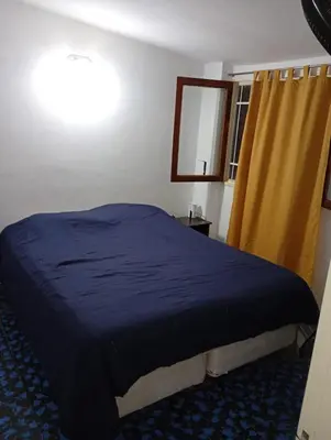 a bedroom with a bed with a blue blanket and a window at Hermosa Casa equipada a metros del Río Cosquín in Bialet Massé