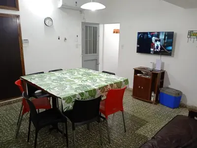 a dining room table with red chairs and a television at Hermosa Casa equipada a metros del Río Cosquín in Bialet Massé
