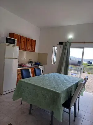 a kitchen with a table with chairs and a refrigerator at Colibrí Del Lago in Villa Parque Siquiman
