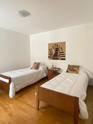two beds in a room with white walls and wooden floors at Departamento Nuñez in Cordoba