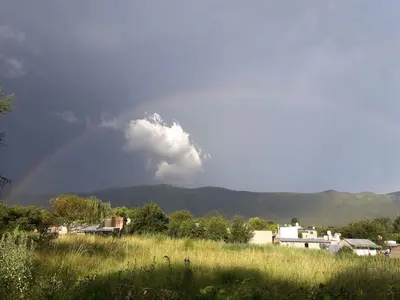 a rainbow over a field with a mountain in the background at Casitas Serranas en Santa María de Punilla in Santa María
