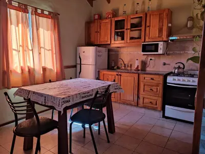 a kitchen with a table and chairs and a refrigerator at No tiene nombre in Mina Clavero